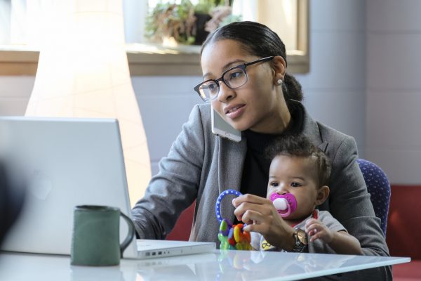 Mother holding baby and working at her computer